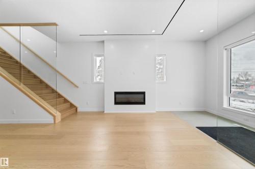 Expansive living space featuring light hardwood flooring, a modern fireplace, and large windows that provide abundant natural light - 14037 104 Avenue, Edmonton, AB - Indoor With Fireplace