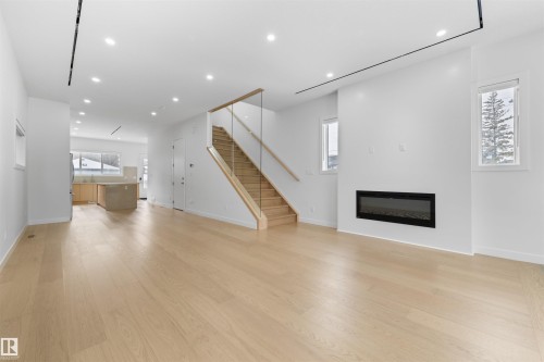 This open-concept living area features light hardwood flooring, recessed lighting, and a linear fireplace - 14037 104 Avenue, Edmonton, AB - Indoor Photo Showing Living Room With Fireplace