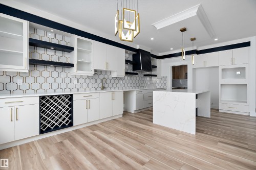 This bright kitchen features white cabinetry, a stylish geometric backsplash, and a central island with a quartz countertop - 219 Crystal Creek Dr, Leduc, AB - Indoor Photo Showing Kitchen With Upgraded Kitchen