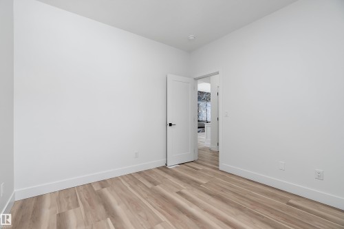 This room features light-colored plank flooring, white walls, and a white door with black hardware - 219 Crystal Creek Dr, Leduc, AB - Indoor Photo Showing Other Room