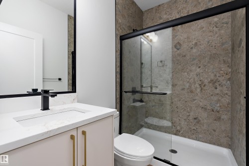 This bathroom features a contemporary vanity with a white countertop and gold-toned hardware, a matte black faucet, and a large mirror with a black frame - 219 Crystal Creek Dr, Leduc, AB - Indoor Photo Showing Bathroom