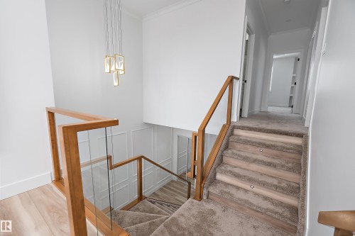 This property features a modern staircase with carpeted treads and integrated lighting, complemented by a wood and glass banister - 219 Crystal Creek Dr, Leduc, AB - Indoor Photo Showing Other Room