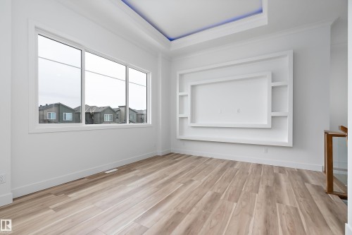 This bright room features a large window, light-toned wood flooring, and a built-in media center with shelving - 219 Crystal Creek Dr, Leduc, AB - Indoor Photo Showing Other Room