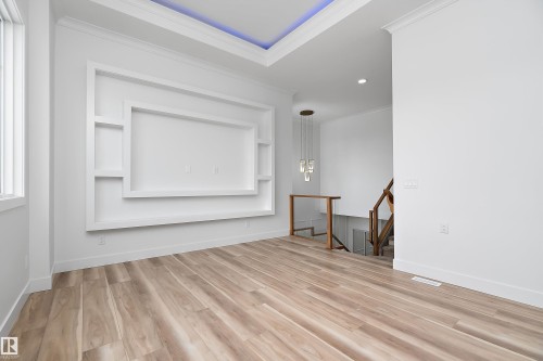 This bright room features light-toned wood flooring and a built-in white media wall with shelving - 219 Crystal Creek Dr, Leduc, AB - Indoor Photo Showing Other Room