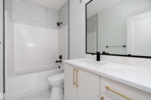 Modern bathroom featuring a white bathtub, a tiled shower surround, a vanity with a white countertop, and a large mirror with a black frame - 219 Crystal Creek Dr, Leduc, AB - Indoor Photo Showing Bathroom