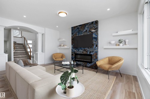 Spacious living area featuring light-toned flooring, an elegant fireplace with a unique blue and brown accent wall, and recessed lighting - 219 Crystal Creek Dr, Leduc, AB - Indoor Photo Showing Living Room