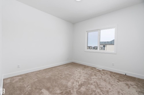 This room features neutral-toned carpeting, white walls, and a window providing natural light - 219 Crystal Creek Dr, Leduc, AB - Indoor Photo Showing Other Room