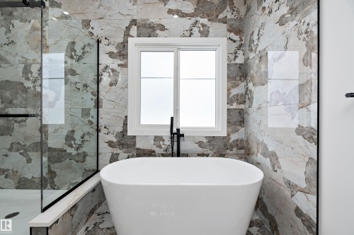 This bathroom features a contemporary freestanding bathtub set against a wall with a window, providing natural light - 219 Crystal Creek Dr, Leduc, AB - Indoor Photo Showing Bathroom
