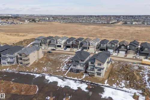 Aerial view of a residential area with several two-story properties featuring attached garages and balconies - 219 Crystal Creek Dr, Leduc, AB - Outdoor With View