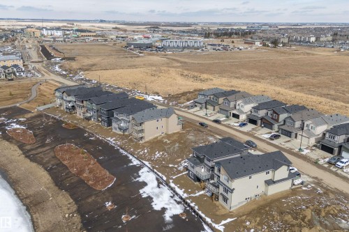 Aerial view of the neighborhood featuring properties with dark-colored roofs and light-colored exteriors, along with streets and surrounding open land - 219 Crystal Creek Dr, Leduc, AB - Outdoor With View