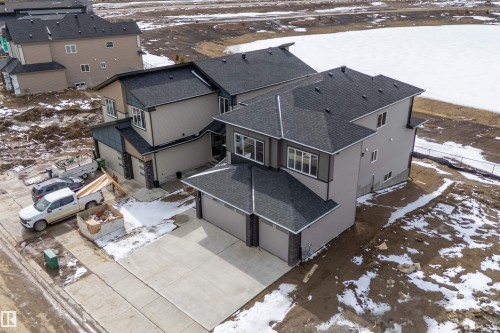 This property features a contemporary exterior with a dark shingle roof, light-colored siding, and a spacious paved driveway - 219 Crystal Creek Dr, Leduc, AB - Outdoor With Deck Patio Veranda
