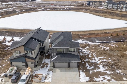 The property features a dark gray shingled roof and light gray siding, complemented by darker gray accents around the windows and garage doors - 219 Crystal Creek Dr, Leduc, AB - Outdoor