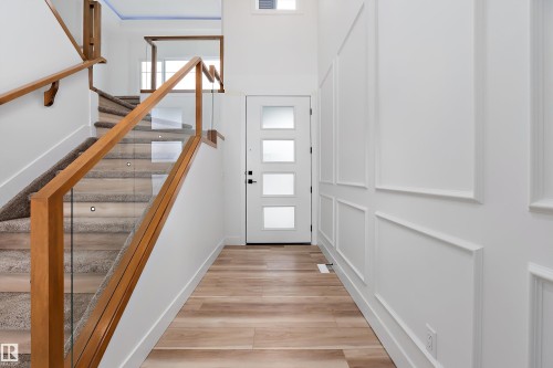 Inviting entryway featuring light wood flooring, a white front door with frosted glass panels, and decorative wall molding - 219 Crystal Creek Dr, Leduc, AB - Indoor Photo Showing Other Room