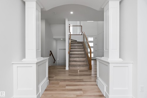 The entryway features light-toned wood flooring, decorative white columns, and an arched ceiling detail - 219 Crystal Creek Dr, Leduc, AB - Indoor Photo Showing Other Room
