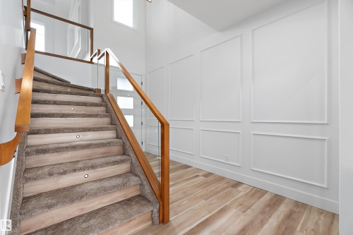 Staircase featuring carpeted treads, wood handrails, and glass balustrades - 219 Crystal Creek Dr, Leduc, AB - Indoor Photo Showing Other Room