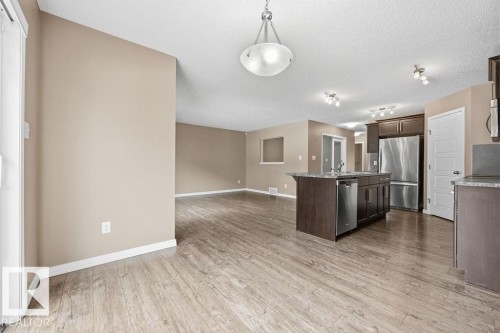 The open concept living area features light wood-style flooring, neutral wall colors, and recessed lighting throughout - 7873 170A Avenue, Edmonton, AB - Indoor Photo Showing Kitchen With Stainless Steel Kitchen