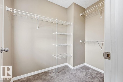 This walk-in closet features wire shelving, a hanging rod, and carpeted flooring - 7873 170A Avenue, Edmonton, AB - Indoor With Storage
