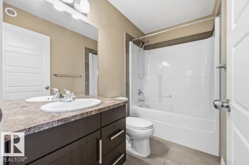 Bathroom featuring a double vanity with ample counter space, a large mirror, and a combination shower and tub with a shower curtain rod - 7873 170A Avenue, Edmonton, AB - Indoor Photo Showing Bathroom