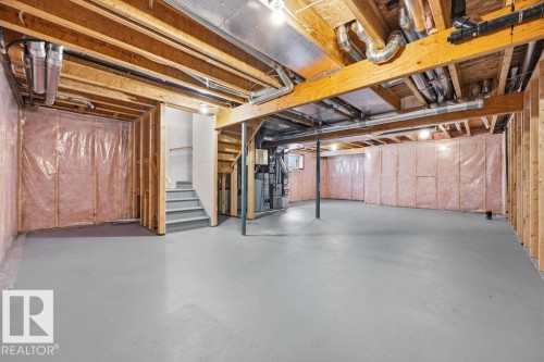 Unfinished basement featuring exposed wooden beams and structural elements, a staircase with gray treads, and ample open space - 7873 170A Avenue, Edmonton, AB - Indoor Photo Showing Basement