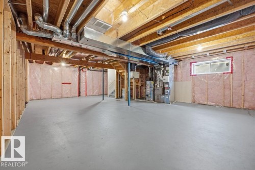Unfinished basement with exposed wooden beams, a painted concrete floor, and insulation along the perimeter walls - 7873 170A Avenue, Edmonton, AB - Indoor Photo Showing Basement