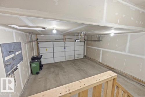 The property features a garage with a concrete floor, an overhead door, and exposed drywall - 7873 170A Avenue, Edmonton, AB - Indoor Photo Showing Garage