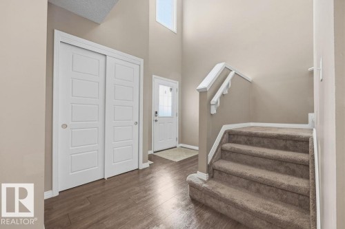 Entryway featuring hardwood style flooring, a carpeted staircase with white railings, and a front door with a decorative glass insert - 7873 170A Avenue, Edmonton, AB - Indoor Photo Showing Other Room