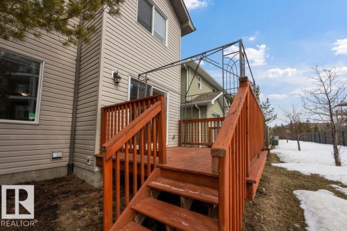 The property features a wooden deck with railing, a metal pergola structure, and siding exterior - 7873 170A Avenue, Edmonton, AB - Outdoor