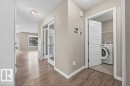 The property features wood-look flooring throughout the main hallway, leading to a room with a window providing natural light - 7873 170A Avenue, Edmonton, AB  - Indoor Photo Showing Laundry Room 
