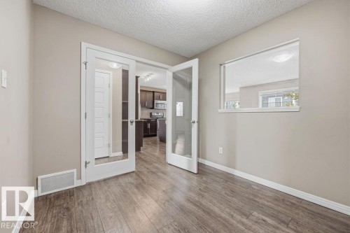 The property features warm-toned hardwood floors, light neutral walls, and white trim - 7873 170A Avenue, Edmonton, AB - Indoor Photo Showing Other Room