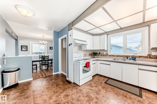 This kitchen features white cabinetry, a tiled backsplash, and an integrated oven/range - 7512 136 Avenue, Edmonton, AB - Indoor Photo Showing Kitchen With Double Sink