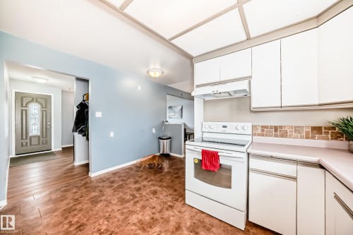 Kitchen area featuring white cabinetry, an electric stove, and a tiled backsplash - 7512 136 Avenue, Edmonton, AB - Indoor Photo Showing Kitchen