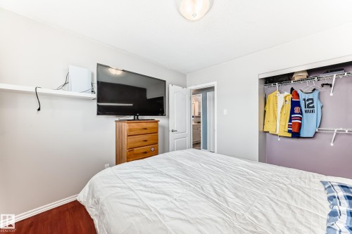 This room features hardwood flooring, light-colored walls, a closet with shelving and hanging space, and a ceiling-mounted light fixture - 7512 136 Avenue, Edmonton, AB - Indoor Photo Showing Bedroom