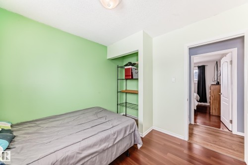 The property features interior rooms with hardwood flooring, light green walls, and white trim - 7512 136 Avenue, Edmonton, AB - Indoor Photo Showing Bedroom