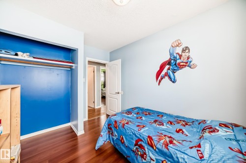 The room features hardwood flooring, light blue walls, and an open closet with a blue interior - 7512 136 Avenue, Edmonton, AB - Indoor Photo Showing Bedroom