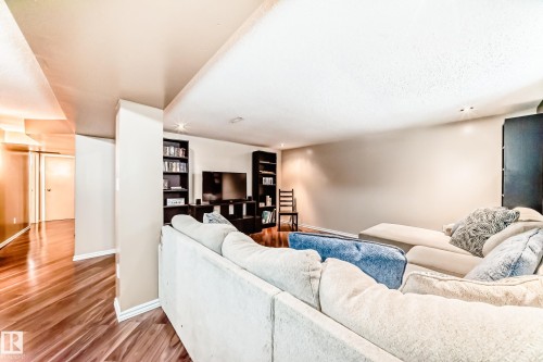 This living area features a light-colored sectional sofa, recessed lighting, and built-in shelving - 7512 136 Avenue, Edmonton, AB - Indoor