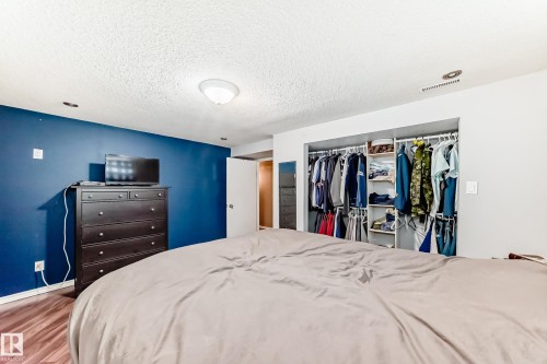 Bedroom featuring hardwood flooring, a contrasting accent wall, and a built-in closet with shelving and hanging space - 7512 136 Avenue, Edmonton, AB - Indoor Photo Showing Bedroom