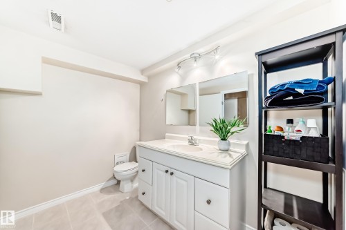Bathroom featuring a white vanity with a sink, a toilet, a mirror, and tiled flooring - 7512 136 Avenue, Edmonton, AB - Indoor Photo Showing Bathroom
