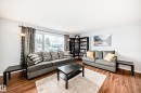 Living room featuring wood-look flooring, light-colored walls, and a large window with patterned drapes - 7512 136 Avenue, Edmonton, AB  - Indoor Photo Showing Living Room 