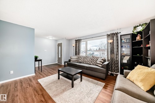 Inviting living area featuring hardwood flooring, light blue walls, and a large window providing natural light - 7512 136 Avenue, Edmonton, AB - Indoor Photo Showing Living Room