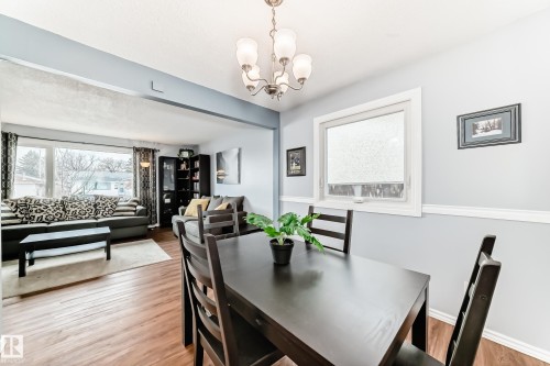 The property features distinct living and dining areas, both with wood-look flooring - 7512 136 Avenue, Edmonton, AB - Indoor Photo Showing Dining Room