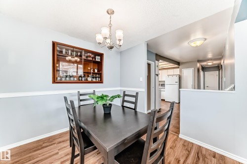 The dining area features hard flooring, light-colored walls with a chair rail, and an overhead chandelier - 7512 136 Avenue, Edmonton, AB - Indoor Photo Showing Dining Room