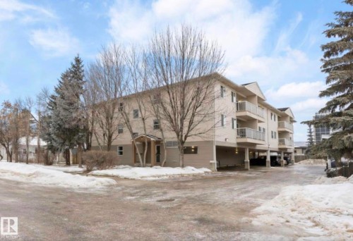 The property features a multi-story building with balconies and an integrated covered parking area - 103 12110 119 Ave, Edmonton, AB - Outdoor