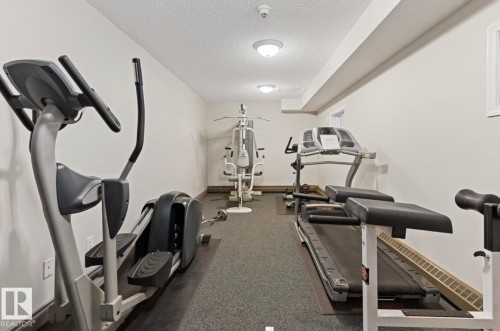 The property includes a well-equipped fitness area with various exercise machines, recessed lighting, and durable carpet flooring - 103 12110 119 Ave, Edmonton, AB - Indoor Photo Showing Gym Room