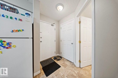 The property features a well-lit entry with a flush mount ceiling light, light-colored walls, and patterned flooring - 103 12110 119 Ave, Edmonton, AB - Indoor Photo Showing Other Room