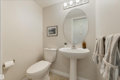 Well-appointed washroom featuring a pedestal sink, an oval mirror, and a toilet - 67 12050 17 Avenue, Edmonton, AB - Indoor Photo Showing Bathroom