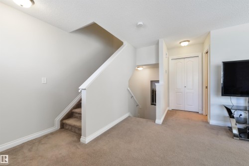 The property features a staircase with carpeted steps and white railings, a carpeted floor, white walls, and flush mount lighting fixtures - 67 12050 17 Avenue, Edmonton, AB - Indoor Photo Showing Other Room