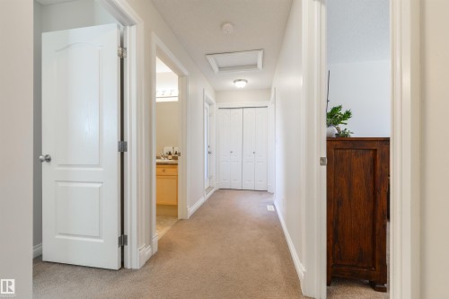 Hallway with carpet flooring and white painted walls, featuring white interior doors and bi-fold closet doors - 67 12050 17 Avenue, Edmonton, AB - Indoor Photo Showing Other Room