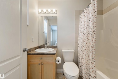 The bathroom features a vanity with a light wood cabinet and a countertop, a toilet, and a bathtub with tiled surround - 67 12050 17 Avenue, Edmonton, AB - Indoor Photo Showing Bathroom