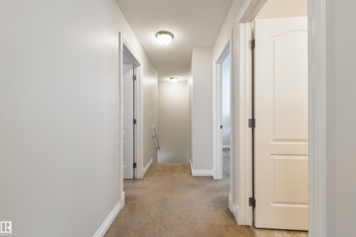 The property features a bright hallway with light-colored walls and carpeted flooring - 67 12050 17 Avenue, Edmonton, AB - Indoor Photo Showing Other Room