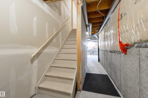 The unfinished basement presents an opportunity for customization, featuring a concrete floor, concrete walls, exposed ductwork, and partially finished drywall - 67 12050 17 Avenue, Edmonton, AB - Indoor Photo Showing Other Room